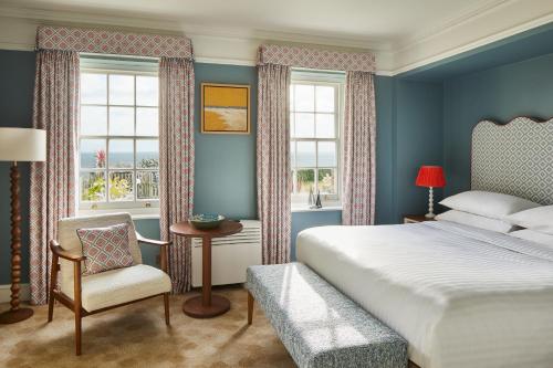 a bedroom with a bed and a chair and windows at Bournemouth Highcliff Marriott Hotel in Bournemouth