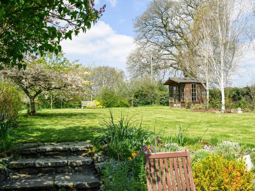 a wooden chair sitting in a garden with a cabin at Wheelwright Cottage in Clunbury