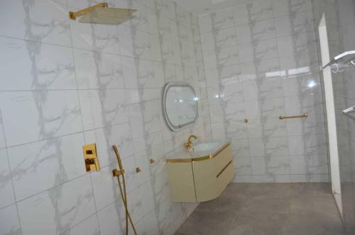 a white tiled bathroom with a sink and a shower at Villa Keur Carla in Niangol