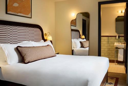 a bedroom with a large white bed and a bathroom at The Hoxton, Dublin in Dublin