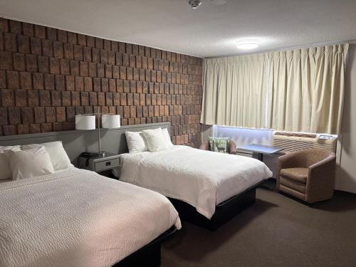 a hotel room with two beds and a chair at Companion Hotel Motel in Hearst