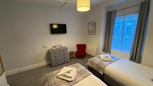 a bedroom with two beds and a red chair at Anglebury House in Wareham