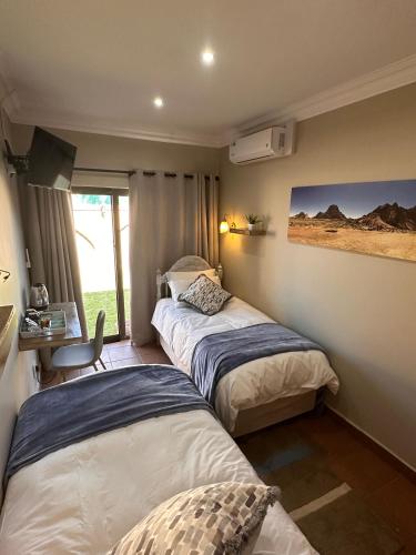 a room with two beds and a desk and a window at 20 at Meul in Potchefstroom