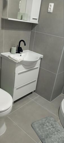 a white bathroom with a sink and a toilet at LevelUP in Đakovo