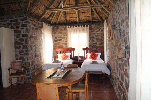 a room with two beds and a table and chairs at Tsauchab River Camp in Sesriem