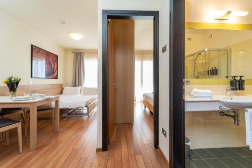 a bathroom with a sink and a living room at Bibione Palace Hotel in Bibione