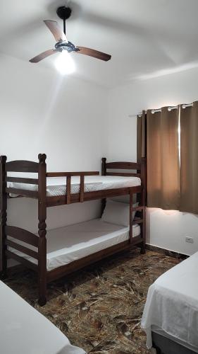 a room with two bunk beds and a ceiling fan at Casa do Sol II in Peruíbe
