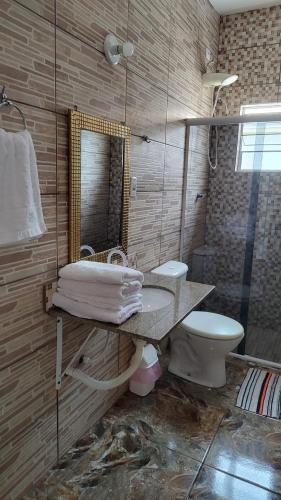 a bathroom with a toilet and a sink and a mirror at Casa do Sol II in Peruíbe