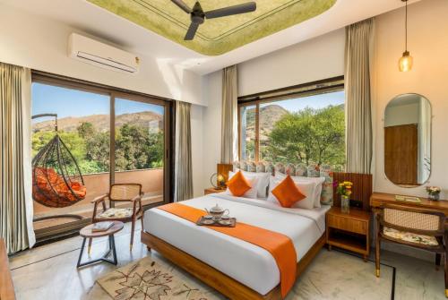 a bedroom with a bed and a desk and a large window at Shivaangan By Soma Estates in Udaipur