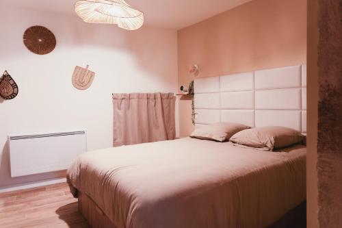 a bedroom with a large bed with a white headboard at La Parenthèse Yssoirienne - Balnéo - Vidéoprojecteur in Issoire
