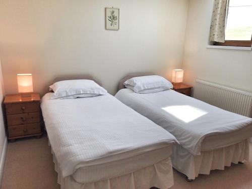 two twin beds in a room with two lamps at Fascadale in Faskadale