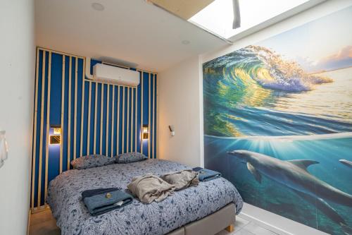 a bedroom with a dolphin painting on the wall at Capsule Océan 2 Chambres- Billard - Jacuzzi - Netflix in Valenciennes