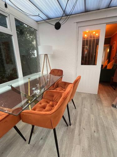 a dining room with a glass table and orange chairs at Stylish 2Bed Ground Floor Flat with Private Garden in Weston-super-Mare