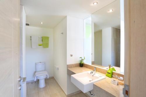 a bathroom with a white sink and a toilet at MaxOneHotels at Bukit Jimbaran in Jimbaran