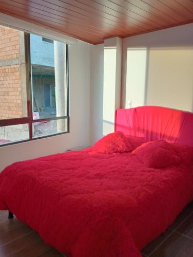 a bedroom with a red bed with a red comforter at Casa punta del este in Paipa