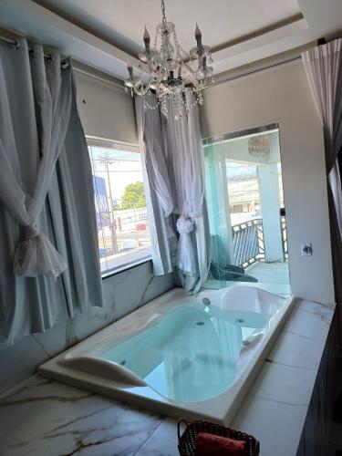 a bath tub in a room with a chandelier at Loft dos sonhos cobertura in Boa Vista