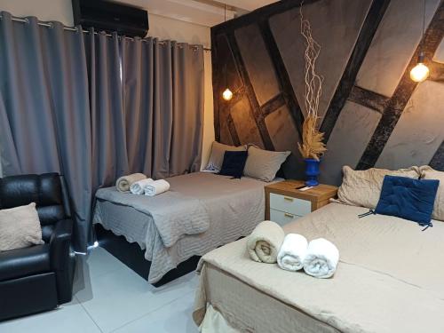 a room with two beds and a chair in it at Loft dos sonhos cobertura in Boa Vista