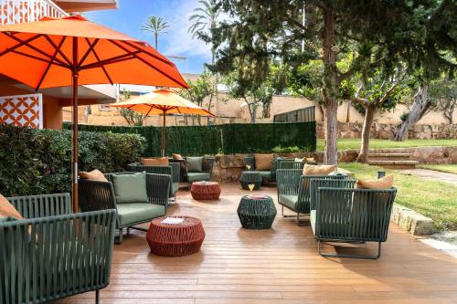 a patio with chairs and tables and an umbrella at Hesperia Mallorca in Palma de Mallorca
