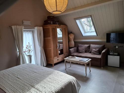 a bedroom with a bed and a couch and a table at B&B 't Heirweggoed in Assenede