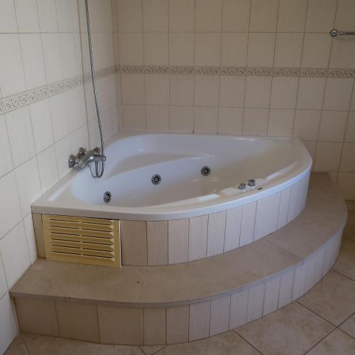 a bath tub in a bathroom with a tile wall at Santos Villa in Quinta do Lago in Quinta do Lago