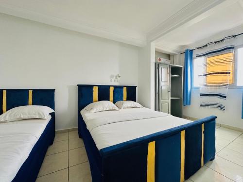 two beds in a room with blue and yellow stripes at CAMERHOME "Low Cost" in Douala