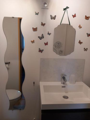 a bathroom with a sink and butterflies on the wall at La maison de Yo in La Feuillée