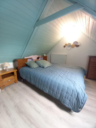 a bedroom with a blue bed in a attic at La maison de Yo in La Feuillée