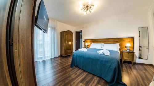 a bedroom with a bed with a blue blanket and a flat screen tv at Paladini al Casale in Piazza Armerina