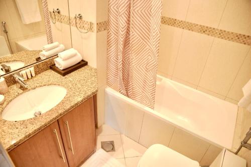 a bathroom with a sink and a toilet and a tub at Stylish 1BR close to Metro and Dubai Marina in Dubai