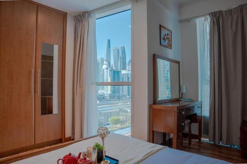 a bedroom with a bed and a desk and a large window at Stylish 1BR close to Metro and Dubai Marina in Dubai