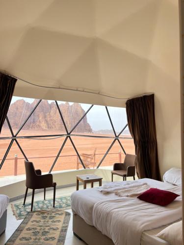 a bedroom with a bed and a large window at Golden Stars Luxury Camp Wadi Rum in Wadi Rum