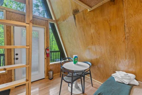 a room with a table and a chair in a cabin at A-Frames Under the Canopy - Multi-Cabin Retreat in Pine Ridge