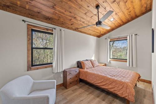 a bedroom with a bed and a chair and two windows at Anchor Point- Hot Tub, Firepit, Ping Pong in Rogers