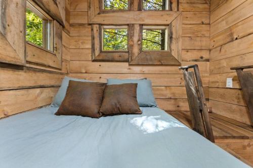 a bed in a room with wooden walls and windows at Amazonia- Pet Friendly, Firepit, Outdoor Shower in Pine Ridge