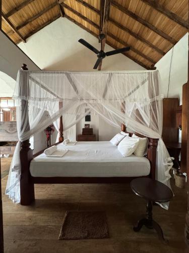 a bedroom with a canopy bed and a table at Villa de Zoysa Yoga, Wellness & Waves in Busse