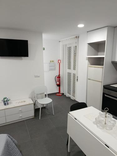a white living room with a table and a tv at Casa Vinhas - O teu refúgio no coração da cidade in Macedo de Cavaleiros