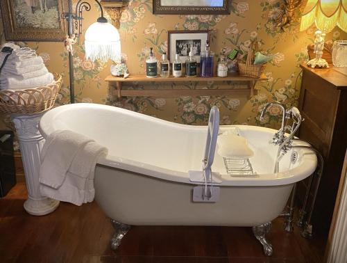 a bath tub in a bathroom with floral wallpaper at The Queen, A Victorian Bed & Breakfast in Bellefonte