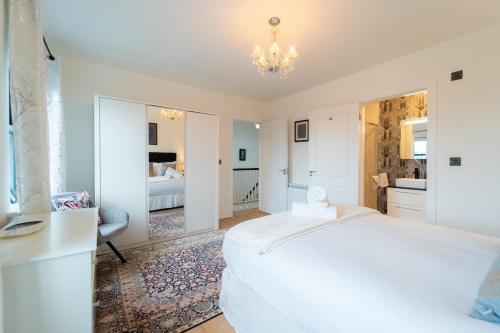 a white bedroom with a bed and a bathroom at Renada Cottage - Dingle Town Centre in Dingle