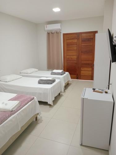 a room with two beds and a television in it at Pousada Jubarte in Serra
