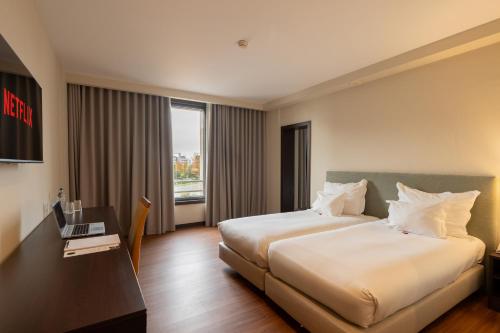 a hotel room with a bed and a desk with a laptop at Hotel Premium Porto Maia in Maia