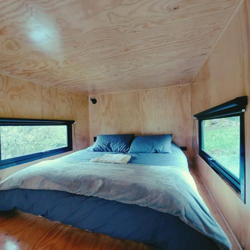 a bed in a tiny house with two windows at La Tiny TINY HAUS in Bogotá