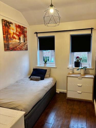 a bedroom with a bed and a desk and two windows at Piotr House in Warrington
