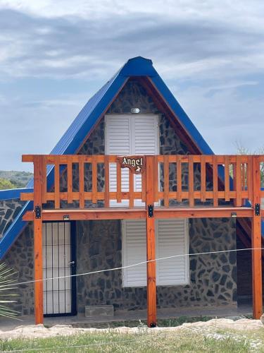 a house with a blue roof and a balcony at Angel Alpino Cabin in Cuesta Blanca