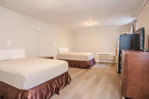 a hotel room with two beds and a flat screen tv at Thunderbird Motel in Savannah