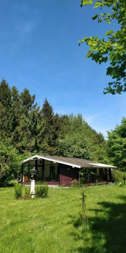 a house in the middle of a grass field at Victorian Summer House On Beautiful Natural Plot in Rønde