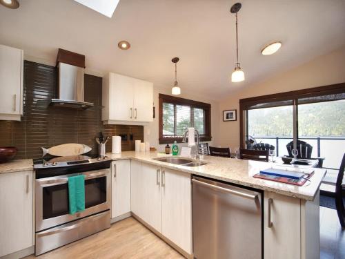 a kitchen with white cabinets and stainless steel appliances at Hera's Cove - Oceanfront Oasis - Pet Friendly in Port Renfrew