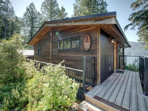 a small cabin with a wooden deck at Hera's Cove - Oceanfront Oasis - Pet Friendly in Port Renfrew