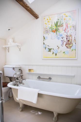 a bath tub in a bathroom with a painting on the wall at Cuckoo Bush Cottage - A unique cottage retreat in Holt