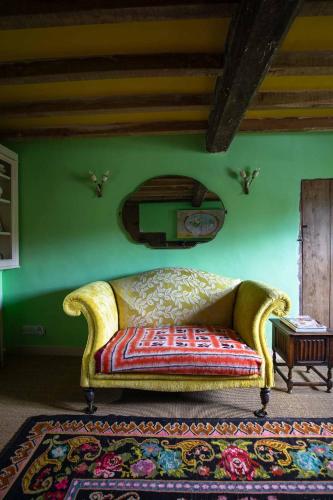 a yellow couch in a room with a green wall at Cuckoo Bush Cottage - A unique cottage retreat in Holt
