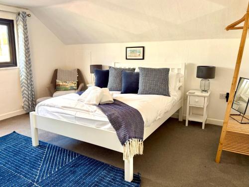 a bedroom with a large white bed with blue pillows at Crows Nest Dawlish in Dawlish